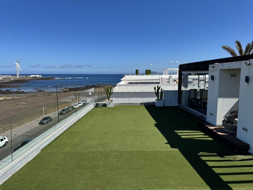 Terraza principal de Endorfina Club con césped artificial y vistas al océano en Corralejo.